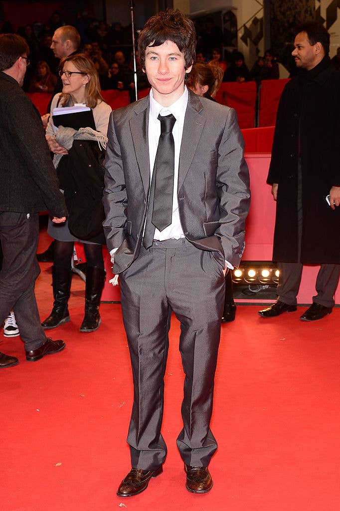 Individual on a red carpet wearing a suit with a tie
