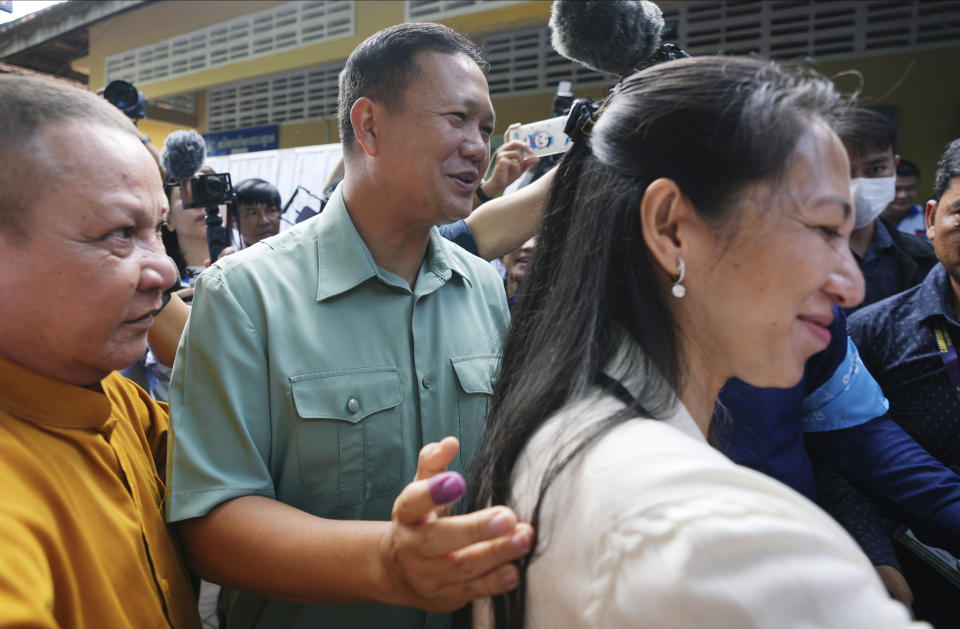 Hun Manet, center, of the Cambodian People's Party (CPP), son of Cambodia Prime Minister Hun Sen, also army chief, walks outside a polling station together with his wife, Pich Chanmony, right, before voting at a polling station in Phnom Penh, Cambodia, Sunday, July 23, 2023. Hun Sen has suggested he will hand off the premiership during the upcoming five-year term to his oldest son, Hun Manet, perhaps as early as the first month after the elections. (AP Photo/Heng Sinith)