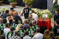 Players of the Campi Corniglianese soccer team gather by the coffin of their teammate Marius Djerri at the exhibition center Fiera di Genoa for the funeral service of some of the victims of a collapsed highway bridge, in Genoa, Italy, Saturday, Aug. 18, 2018. Saturday has been declared a national day of mourning in Italy and includes a state funeral at the industrial port city's fair grounds for those who plunged to their deaths as the 45-meter (150-foot) tall Morandi Bridge gave way Tuesday. (AP Photo/Nicola Marfisi)