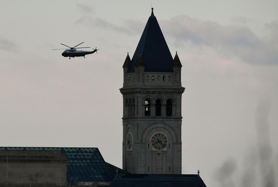 Marine One with US President Donald Trump and First Lady Melania Trump passes the Trump International Hotel (R) as it departs the White House in Washington, DC, on January 20, 2021.