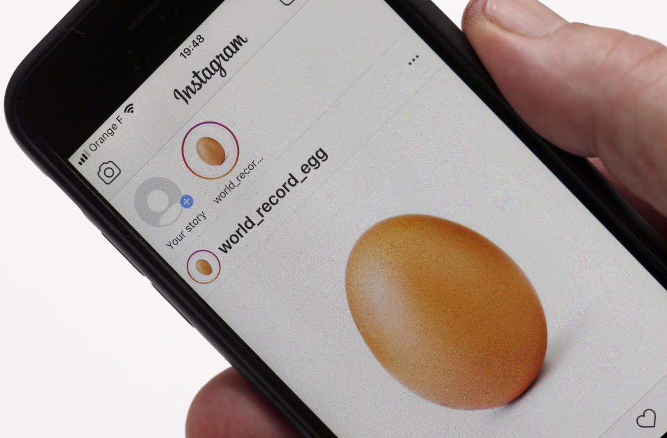 Hand holding a phone showing the Instagram record-breaking egg post