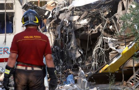 A firefighter works at the site where two passenger trains collided in the middle of an olive grove in the southern village of Corato, near Bari, Italy, July 12, 2016. REUTERS/Alessandro Garofalo