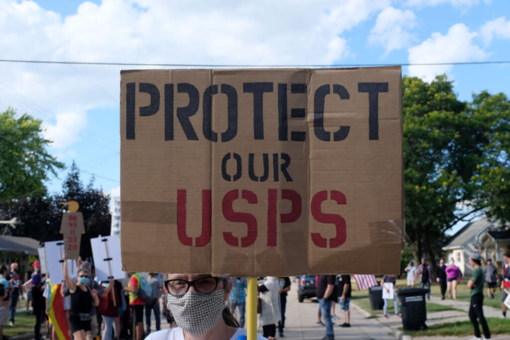 A activists holds a USPS envelope while protesting Donald Trump’s visit on August 17, 2020 in Oshkosh, Wisconsin. (Photo by Alex Wroblewski/Getty Images)