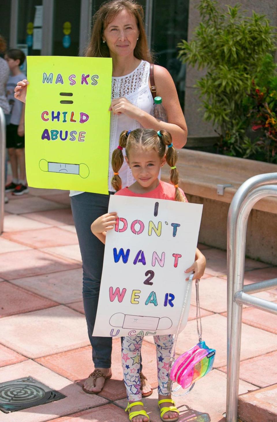 Barbara Rodas holds signs with her 6-year-old daughter, Athena Coletti, outside of the Kathleen C. Wright Administration Building of the Broward School Board in Fort Lauderdale, Tuesday, July 27, 2021. Athena was planning to speak in front of the School Board during a special workshop on COVID-19 safety precautions and potential mask mandates for the upcoming school year. The discussion was postponed until Wednesday after the anti-mask protesters refused to wear masks inside the room where the School Board was meeting.