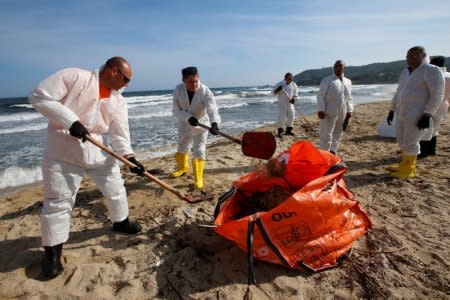 French civil security members remove solid chunks of hydrocarbon on the Plage de Pampelonne beach, in the Gulf of Saint Tropez, near Ramatuelle, France, October 18, 2018 after a collision between two ships off the island of Corsica caused an oil spill.  REUTERS/Jean-Paul Pelissier