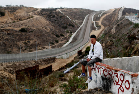 FILE PHOTO: Gerson Antonio Zaldivar, a migrant from Honduras, part of a caravan of thousands traveling from Central America en route to the United States, poses in front of the border wall between the U.S. and Mexico in Tijuana, Mexico, November 24, 2018. REUTERS/Kim Kyung-Hoon