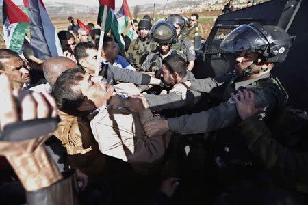 Palestinian minister Ziad Abu Ein (L) scuffles with an Israeli border policeman near the West Bank city of Ramallah December 10, 2014. Abu Ein died shortly after being hit by Israeli soldiers during a protest on Wednesday in the occupied West Bank, a Reuters photographer who witnessed the incident and a Palestinian medic said. REUTERS/Mohamad Torokman