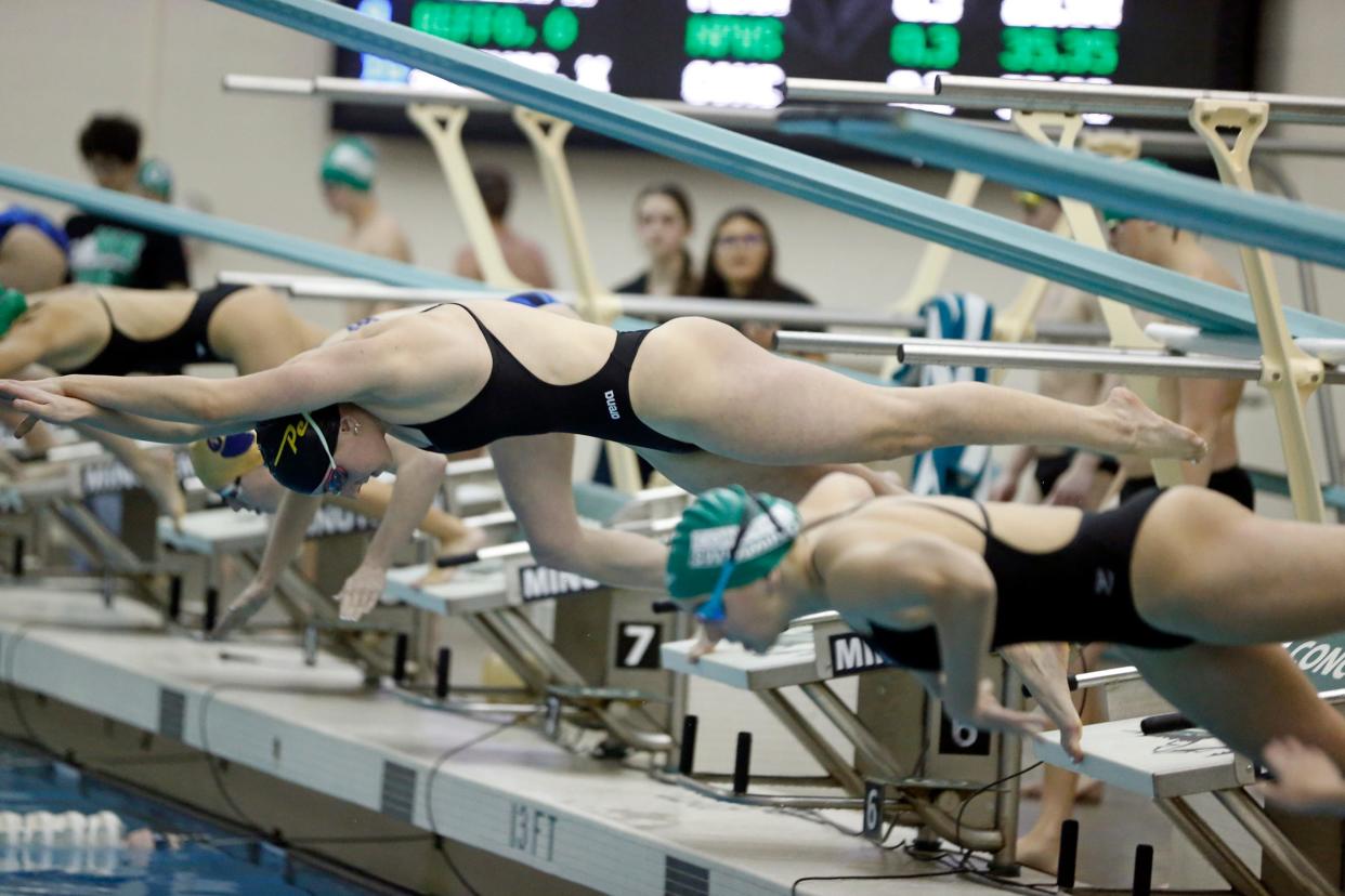 Penn senior Lily Christianson, middle, dives into the pool to start the 50-yard freestyle race during a swimming meet against Concord and New Prairie Thursday, Dec. 14, 2023, at Concord High School in Dunlap.