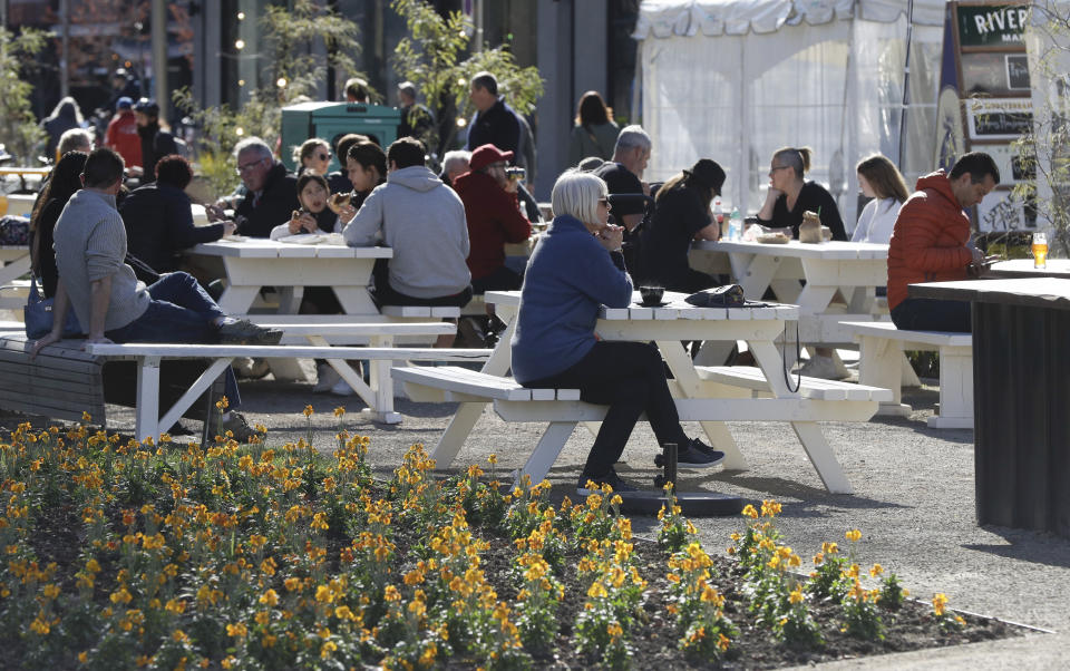 Customers enjoy lunch in the sunshine at the Riverside Market in Christchurch, New Zealand, Sunday, Aug. 9, 2020. New Zealand marked a 100 days of being free from the coronavirus in its communities Sunday, Aug. 9, with just a handful of infections continuing to be picked up at the border where people are quarantined. (AP Photo/Mark Baker)