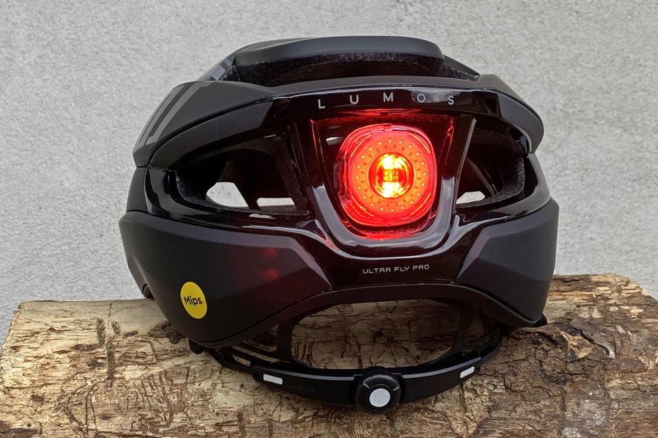 Lumos Ultra Fly Pro MIPS performance road helmet with built-in Firefly taillight, light on