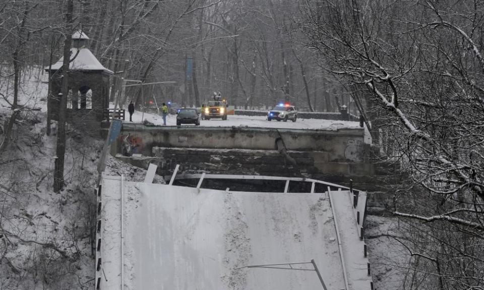 Emergency vehicles parked at the edge of the collapsed bridge.