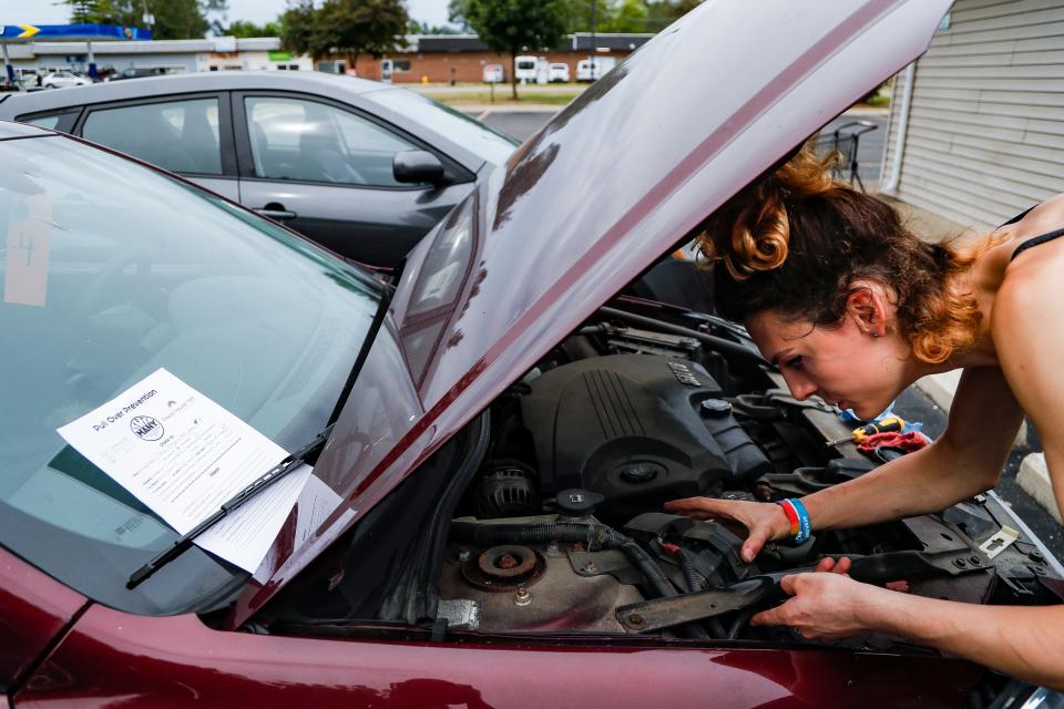 Volunteer Rhiannon Willow checks the voltage on the headlight wiring on a vehicle during Pull Over Prevention at Masjid Ibrahim in Ypsilanti on Saturday, Aug. 13, 2022. Pull Over Prevention is hosted on the second Saturday of every month and it provides free car repairs of lights, tire pressure and fill ups on fluids, as well as free food, pet supplies and more.