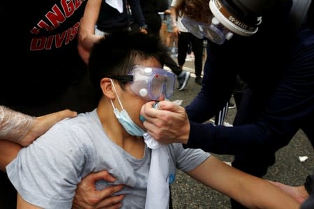 Protesters help a man during a demonstration against a proposed extradition bill where tear gas was fired, in Hong Kong