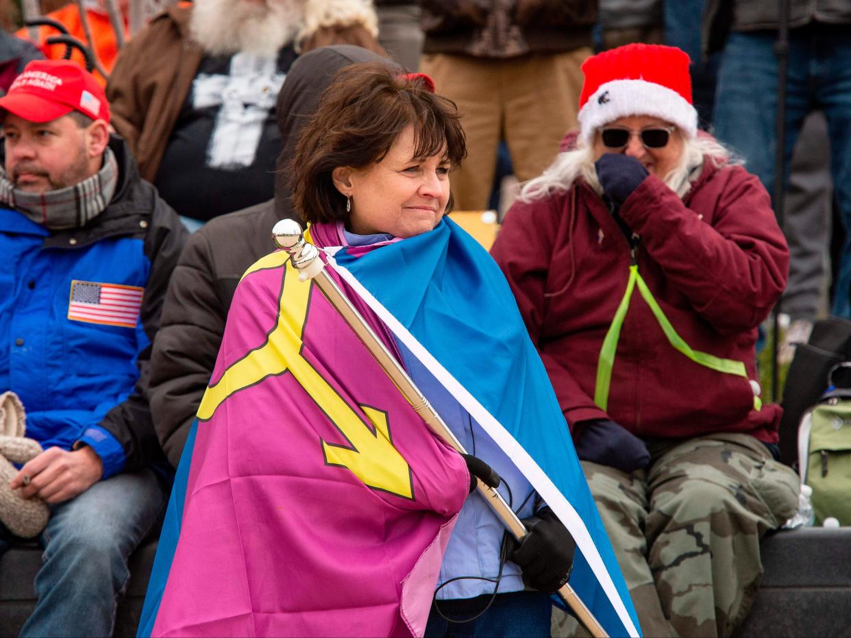 <p>“Super Fun Happy America’s” Sue Ianni wraps herself in the group’s “Straight Pride” flag as she and other supporters of US President Donald Trump wait for him to address them during a rally in Washington, DC on 6 January 2021</p> ((AFP via Getty Images))