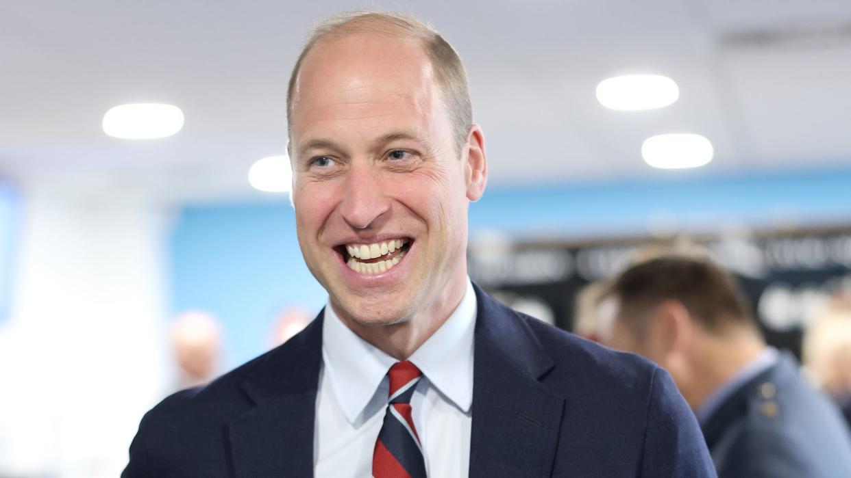 Princw William smiling and holding a mug