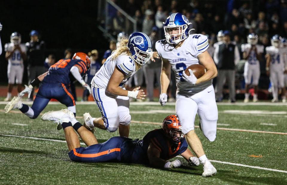 Caldwell's Harry Boland runs the ball as Mountain Lakes defends during the first half of a football game at Mountain Lakes High School on October 21, 2022.