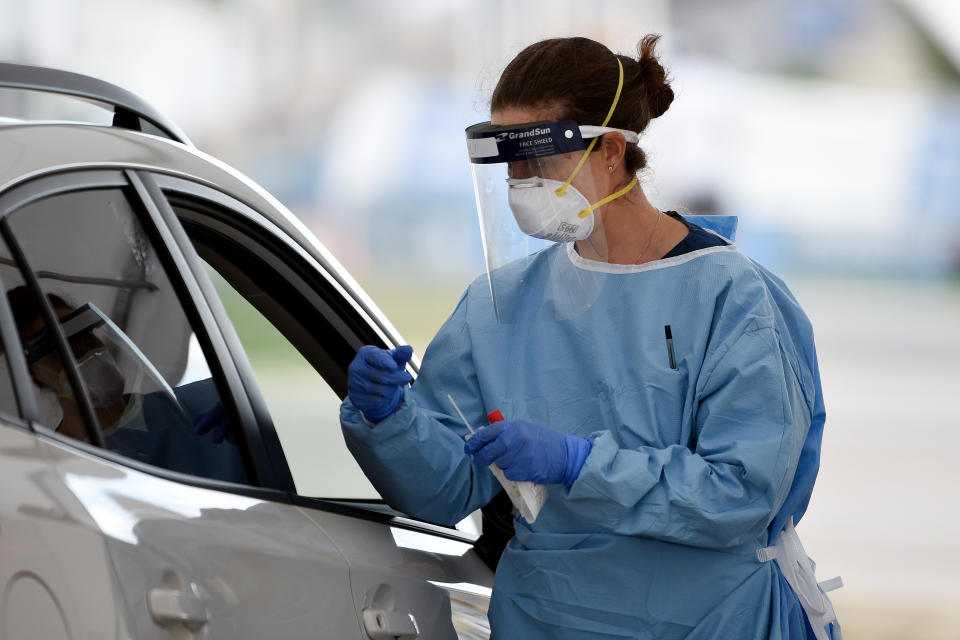 A medical worker performs a COVID-19 test on members of the public at the Bondi Beach drive-through test centre. Source: AAP