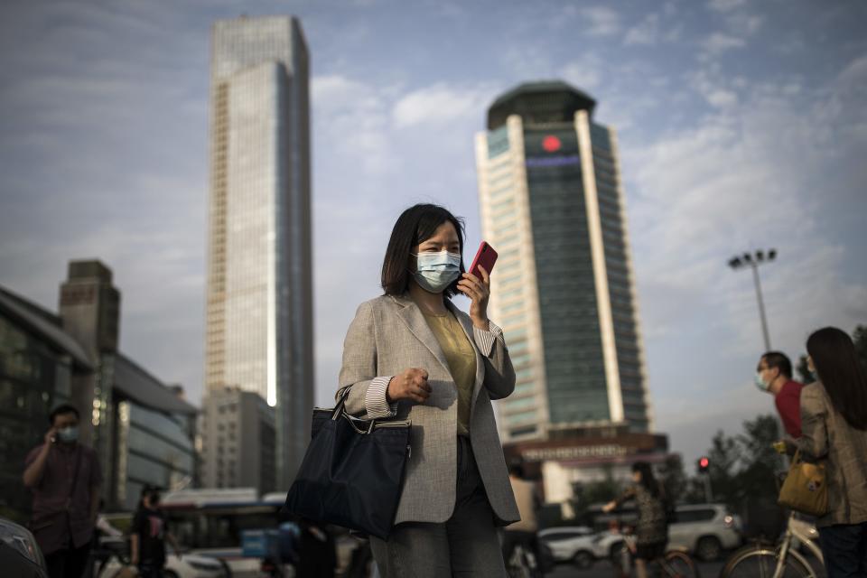 A woman wears a mask while using an iPhone in Wuhan, China.