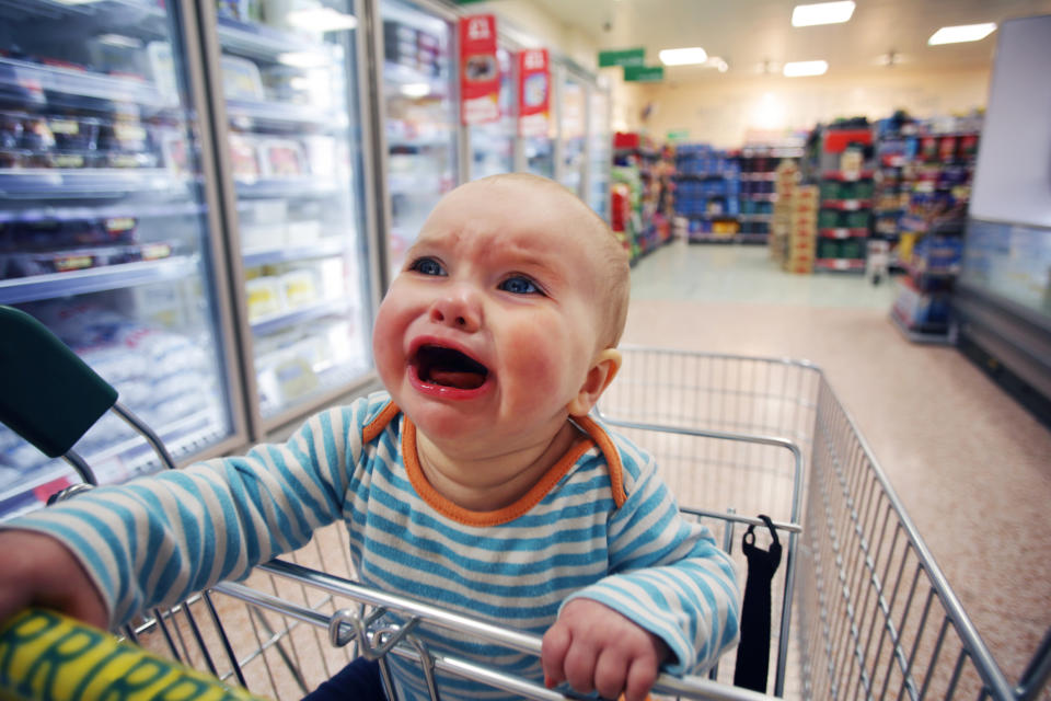 Baby crying in a shopping cart at a grocery store