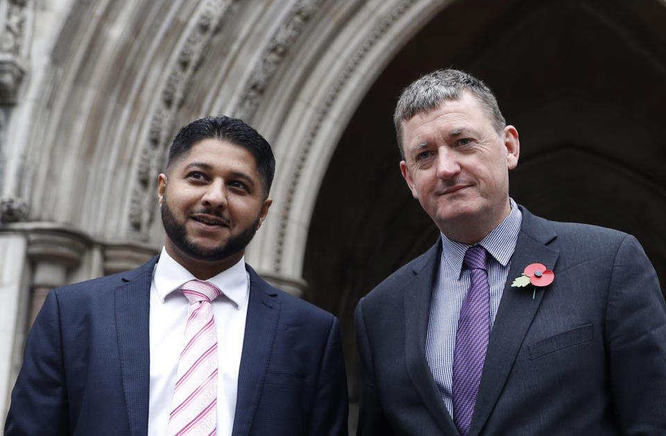 FILE- In this Oct. 30, 2018, file photo, former Uber drivers Yaseen Aslam, left, and James Farrar pose for the media outside the Royal Courts of Justice ahead of a legal hearing over employment rights in London. Uber is giving its U.K. drivers the minimum wage, pensions and holiday pay, following a recent court ruling that said they should be classified as workers and entitled to such benefits, the company announced Tuesday, March 16, 2021. Farrar and Aslam of the App Drivers And Couriers Union said in a statement, the changes stopped short of the Supreme Court's ruling that pay should be calculated from when drivers log on to the app until they log off. And they said the company can't decide by itself the expense base for calculating the minimum wage, which should be based on a collective agreement. (AP Photo/Alastair Grant, File)