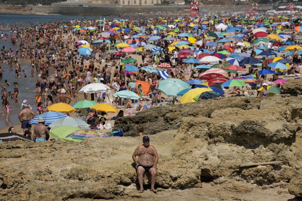 FILE - A man sits in the sun at Carcavelos beach, outside Lisbon, Friday, July 8, 2022. This past year has seen a horrific flood that submerged one-third of Pakistan, one of the three costliest U.S. hurricanes on record, devastating droughts in Europe and China, a drought-triggered famine in Africa and deadly heat waves all over. (AP Photo/Armando Franca, File)
