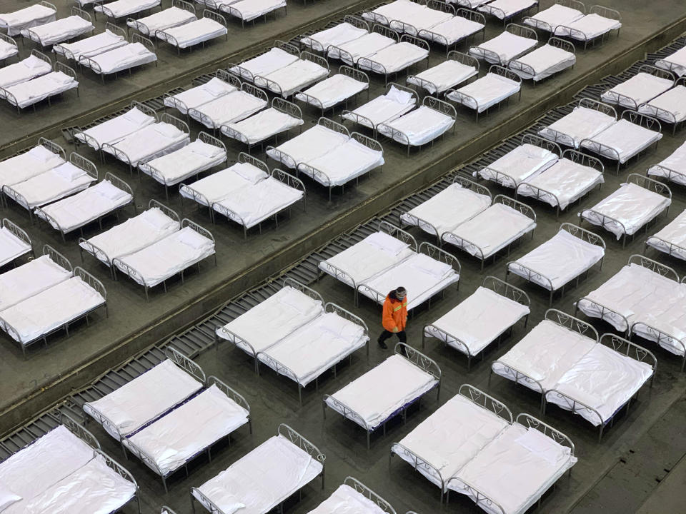 FILE - In this Feb. 4, 2020, file photo workers arrange beds in a convention center that has been converted into a temporary hospital in Wuhan in central China's Hubei Province. (Chinatopix via AP, File)