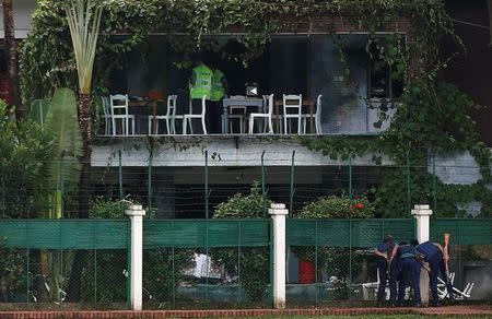 Policemen sneak a look inside the Holey Artisan Bakery and the O'Kitchen Restaurant as others inspect the site after gunmen attacked, in Dhaka, Bangladesh, July 3, 2016. REUTERS/Adnan Abidi/File Photo