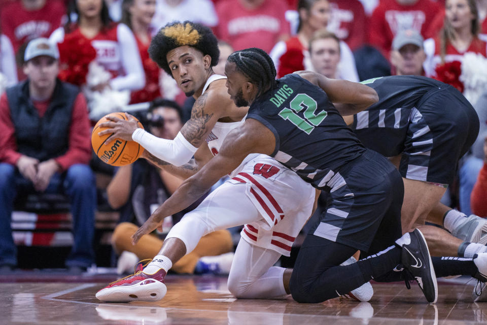 Wisconsin's Chucky Hepburn, left, picks up a loose ball against Chicago State's Brent Davis (12) during the first half of an NCAA college basketball game Friday, Dec. 22, 2023, in Madison, Wis. (AP Photo/Andy Manis)