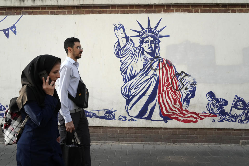 FILE - People walk past a state-organized, anti-U.S. mural painted on the wall of the former U.S. Embassy in Tehran, Iran, on Aug. 19, 2023. U.S. porn actor Whitney Wright, who has advocated for Palestinians online during Israel's war on Hamas, traveled to Iran in Feb. 2024 and visited the former U.S. Embassy in Tehran abandoned after the 1979 hostage crisis. The visit by Wright has sparked heated criticism over the country's crackdown on women since the 2022 death in police custody of Mahsa Amini and the nationwide protests it sparked. (AP Photo/Vahid Salemi, File)