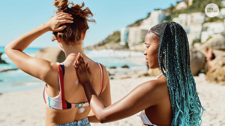 Shot of a young woman applying sunscreen to her friend's back on the beach.