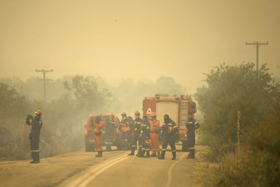 Firefighters stand on the road during a wildfire in Giannouli village, in the northeastern Evros region, Greece, Thursday, Aug. 31, 2023. Greek authorities have further reinforced firefighting forces in the country's northeast, where a massive blaze in its thirteenth day has flared up once more, triggering authorities to issue alerts to residents in the area to be on standby for possible evacuation. (e-evros.gr via AP)