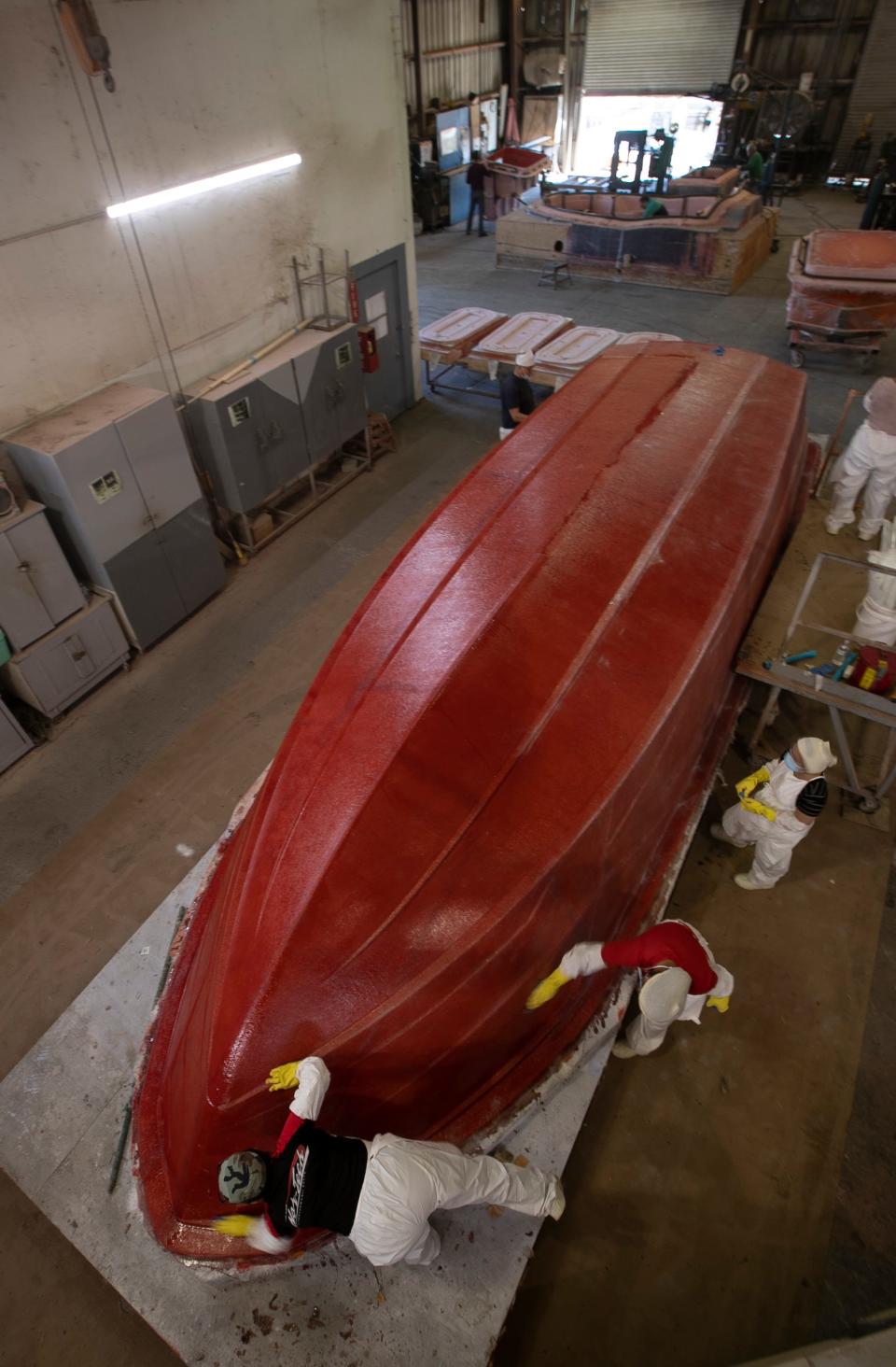 Workers collaborate hand sanding a fiberglass plug under production in January at Marine Concepts.