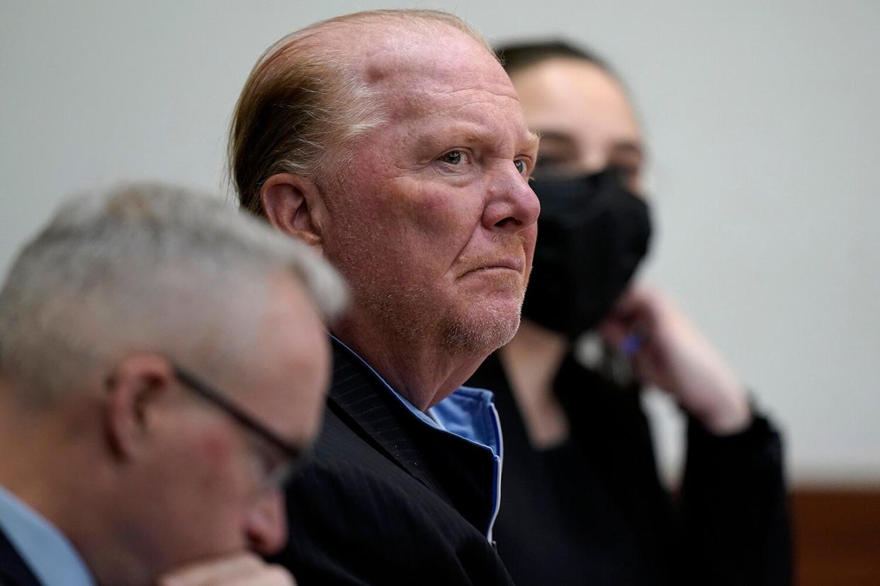 Celebrity chef Mario Batali, center, is seated next to defense attorney Anthony Fuller, left, at Boston Municipal Court for the first day of Batali's pandemic-delayed trial, in Boston. Batali pleaded not guilty to a charge of indecent assault and battery in 2019, stemming from accusations that he forcibly kissed and groped a woman after taking a selfie with her at a Boston restaurant in 2017