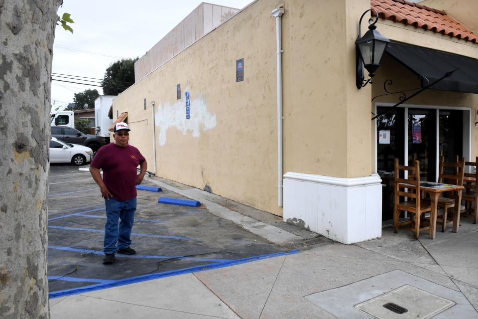 Carlos Reyes, owner of Olas de Carlos Surf Grill in Camarillo, stands over the handicap parking spot for his business on Tuesday, May 9, 2023. The eatery is the subject of a lawsuit alleging that the slope for its disabled access parking spot is out of compliance.