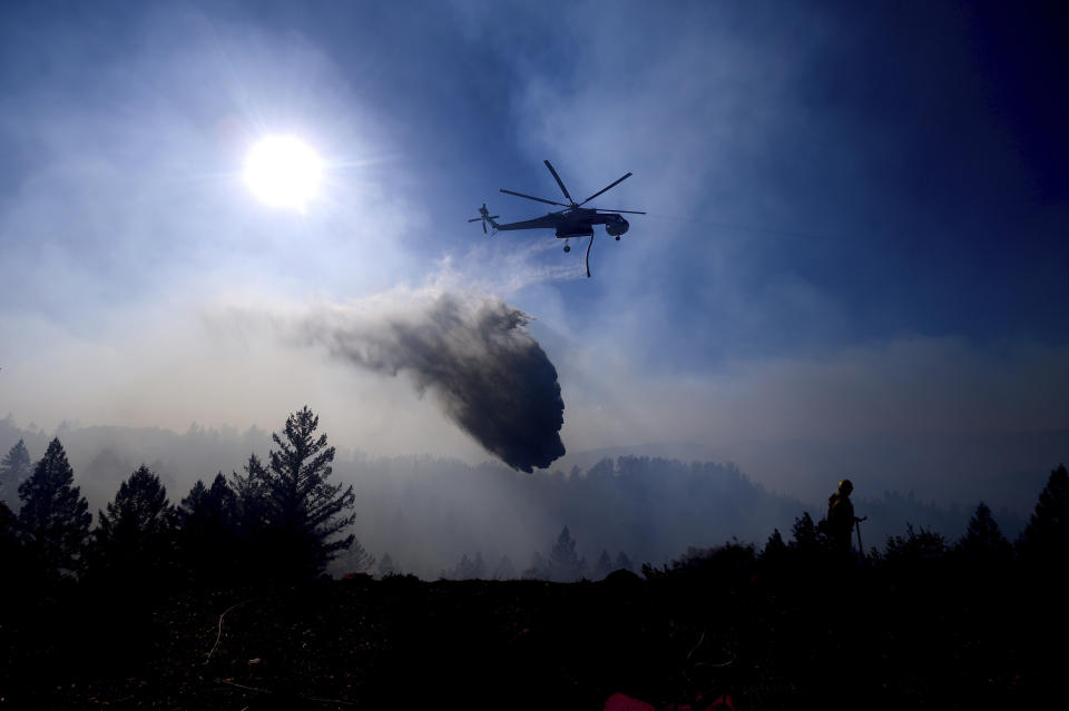 A helicopter drops water while battling the Kincade Fire near Healdsburg, Calif., on Tuesday, Oct. 29, 2019. Millions of people have been without power for days as fire crews race to contain two major wind-whipped blazes that have destroyed dozens of homes at both ends of the state: in Sonoma County wine country and in the hills of Los Angeles. (AP Photo/Noah Berger)