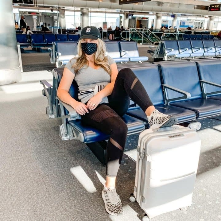 reviewer with their feet kicked up on the white suitcase at the airport