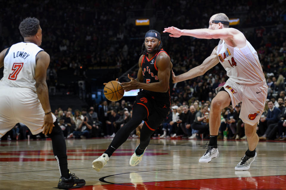 Toronto Raptors forward Precious Achiuwa (5) drives between Miami Heat centre Cody Zeller (44) and guard Kyle Lowry (7) during the first half of an NBA basketball game Tuesday, March 28, 2023, in Toronto. (Christopher Katsarov/The Canadian Press via AP)