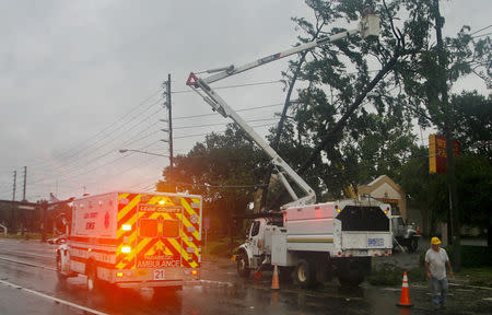 Utility crews cut tree limbs off power lines as an ambulance drives by in the rain and wind from Hurricane Hermine in Tallahassee, Florida, U.S. September 2, 2016. REUTERS/Phil Sears