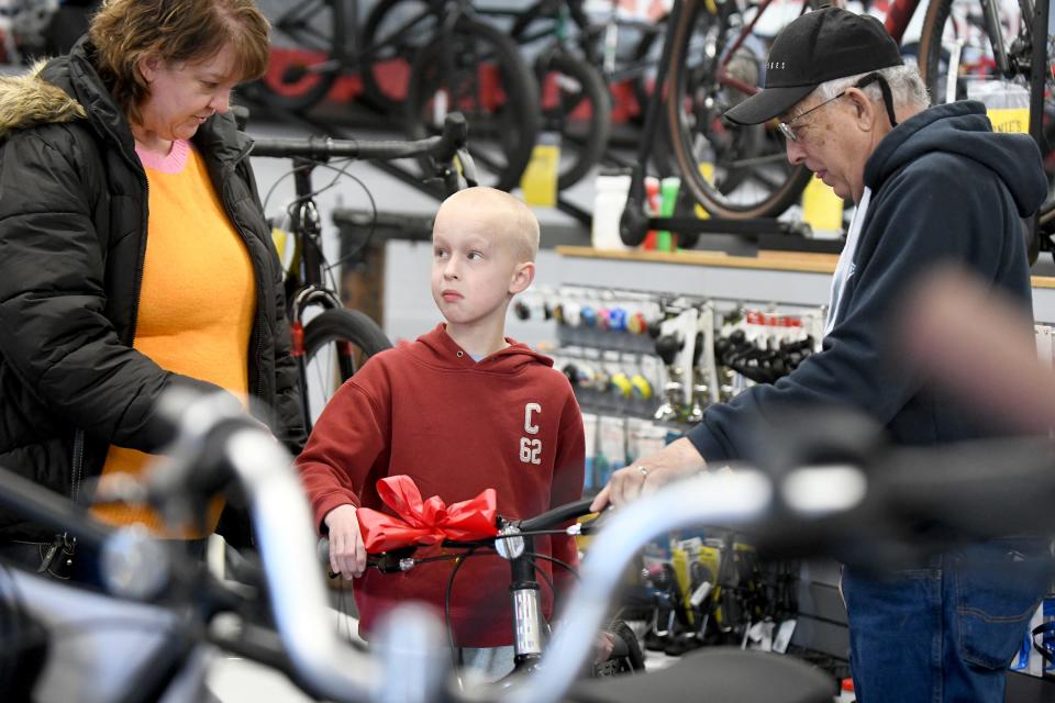 Jordan Owens, 9, who was injured in a Labor Day bicycle accident, and his mother Heather Swiney, get pointers on his new bike from Dave Viola at Ernie's Bike Shop in North Canton, An anonymous donor bought the bike for him after reading a Repository story about the conclusion of the court case against the driver who left the scene of the crash.