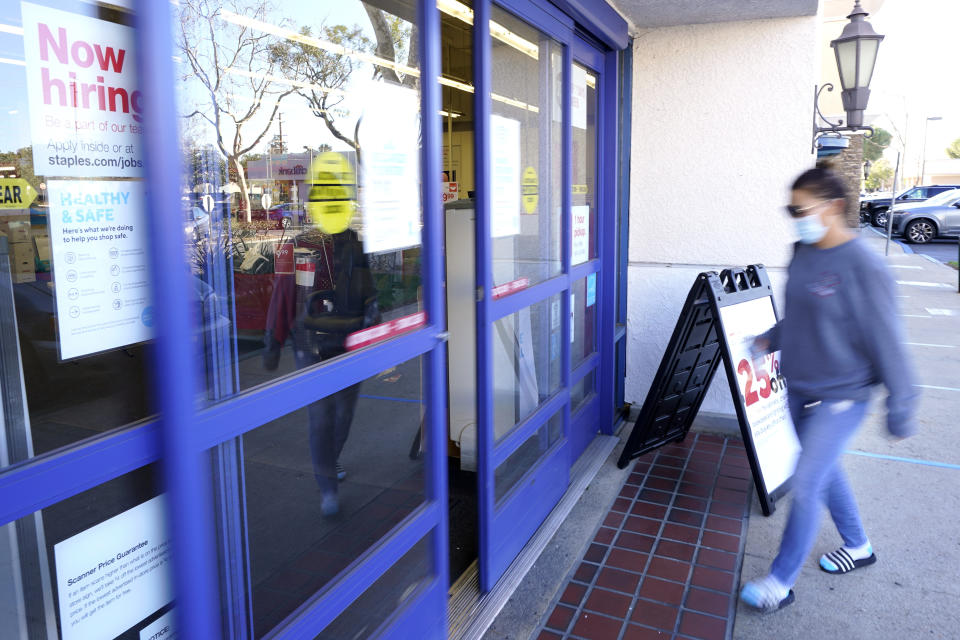 A customer walks by a "Now hiring" sign as she enters a Staple's store, Tuesday, Feb. 2, 2021, in Simi Valley, Calif. Hiring has weakened for six straight months. Nearly 10 million jobs remain lost since the coronavirus struck. And this week, the Congressional Budget Office forecast that employment won’t regain its pre-pandemic level until 2024. (AP Photo/Mark J. Terrill)