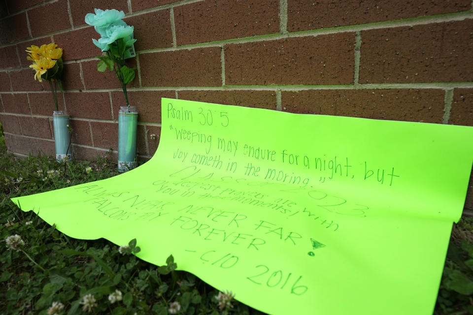 A sign and flowers were placed at the entrance sign for Huguenot High School Wednesday, Jun. 7, 2023, in Richmond, Va. A student form the school and his step-father were killed after a graduation ceremony Tuesday. (Steve Helber)