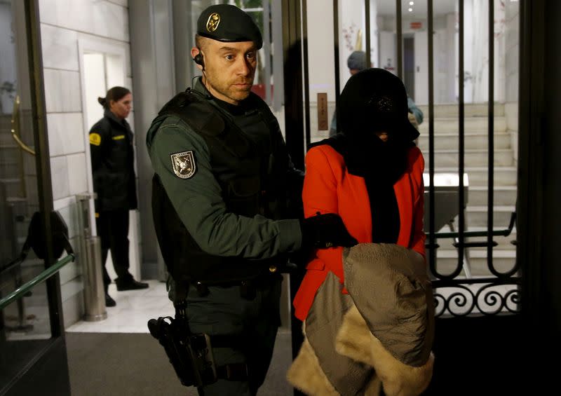 FILE PHOTO: A suspect is led by a Spanish Civil Guard officer as they leave the headquarters of Industrial and Commercial Bank of China (ICBC) during a raid in Madrid