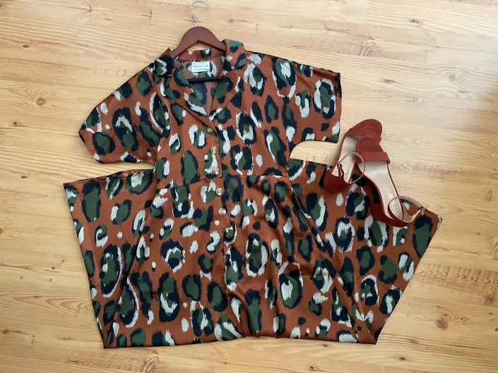 A flatlay of a rust-colored dress with a green animal print and rust-colored heels