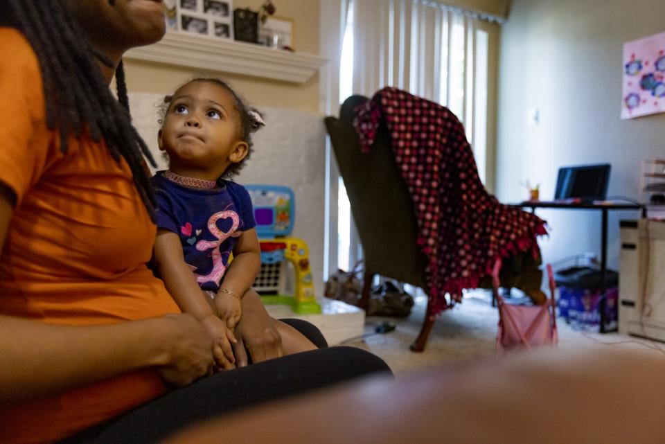 A 27-year-old pregnant woman holds her daughter.