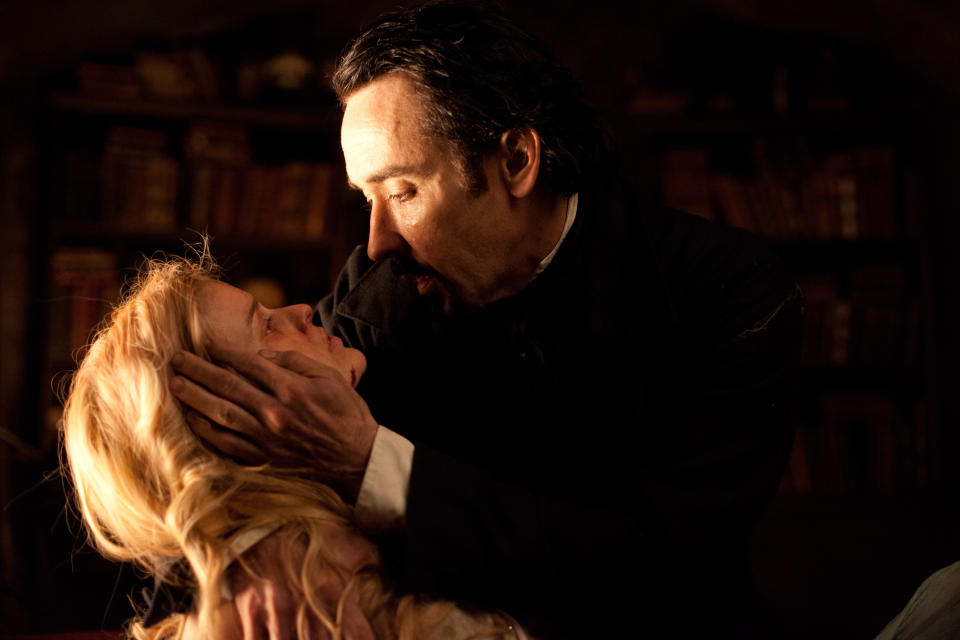 In this film publicity image released by Relativity Media, John Cusack portrays Edgar Allan Poe, right, and Alice Eve portrays Emily Hamilton in a scene from the gothic thriller "The Raven." (AP Photo/Relativity Media, Larry Horricks)