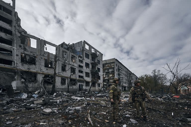 Soldados ucranianos pasan junto a casas arruinadas por los bombardeos rusos en Bakhmut, región de Donetsk, Ucrania,