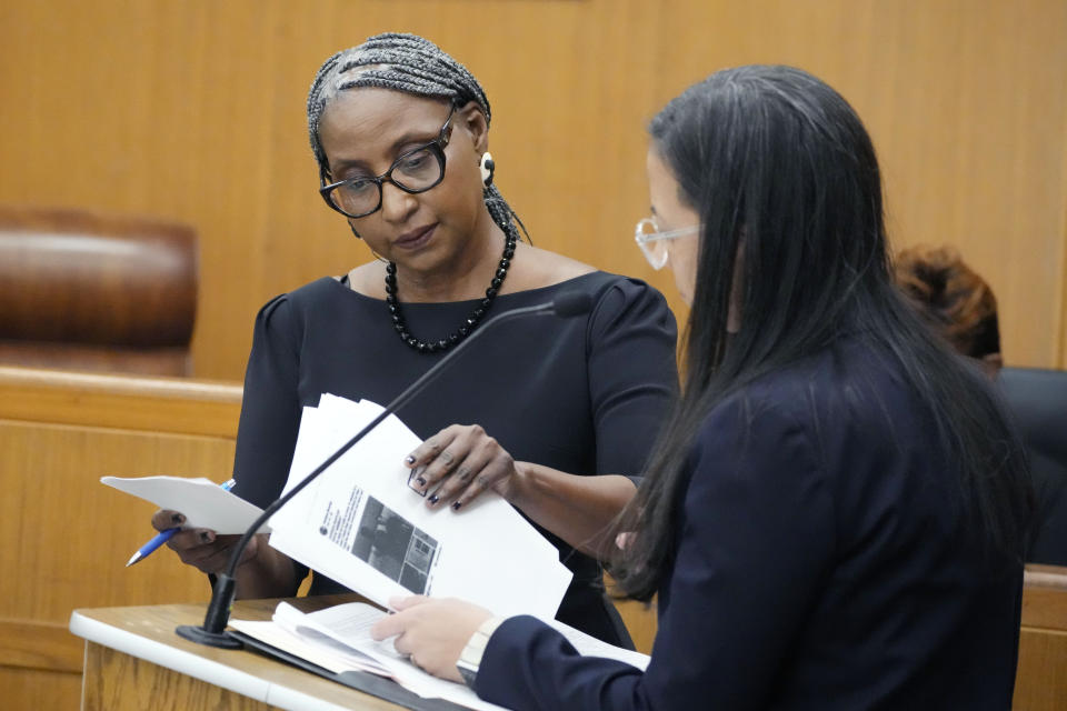 Lisa Ross, attorney for Bul Mabil, brother of Dau Mabil, a 33-year-old Jackson, Miss., resident who went missing on March 25 and whose body was found in April floating in the Pearl River in Lawrence County, left, gives Paloma Wu, attorney for Karissa Bowley, wife of the deceased, a set of her client's texts during a hearing on whether a judge should dissolve or modify his injunction preventing the release of Mabil's remains until an independent autopsy could be conducted, Tuesday, April 30, 2024, in Jackson, Miss. (AP Photo/Rogelio V. Solis)