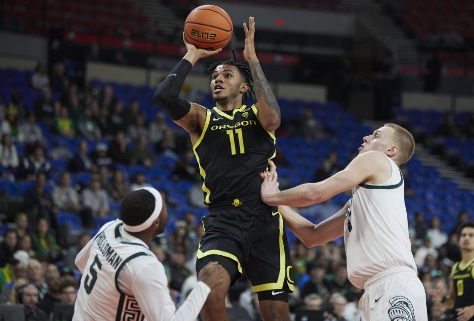 Oregon guard Rivaldo Soares (11) shoots between Michigan State guard Tre Holloman (5) and forward Joey Hauser during the first half of an NCAA college basketball game in the Phil Knight Invitational tournament in Portland, Ore., Friday, Nov. 25, 2022. (AP Photo/Craig Mitchelldyer)