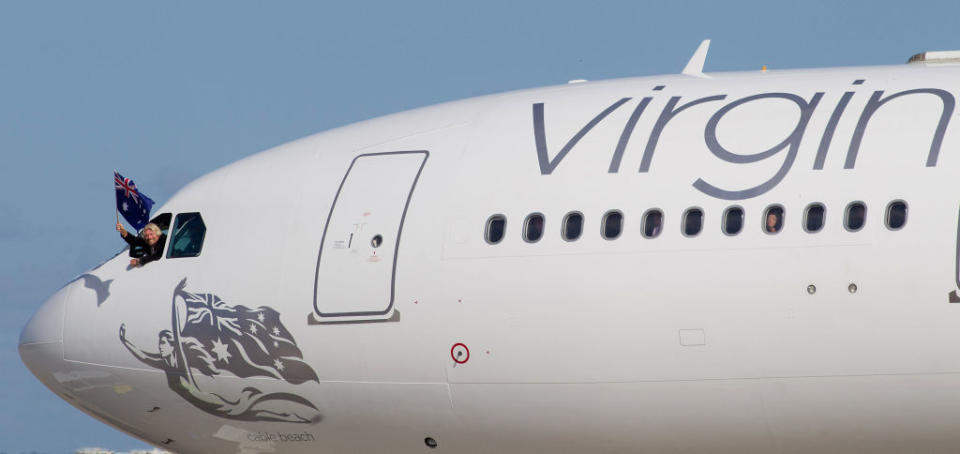 Sir Richard Branson, founder of the Virgin Group waves an Australian flag from the cockpit of a A-330 passenger jet after touching down in Sydney, Australia, on Wednesday, May 4, 2011. Branson and John Borghetti, CEO, Virgin Blue Group of Airlines unveiled the new look and re-naming of Virgin Blue to Virgin Australia at a media conference and event at Sydney Airport. Photographer: Ian Waldie/Bloomberg    ***Local Caption***    Sir Richard Branson. 