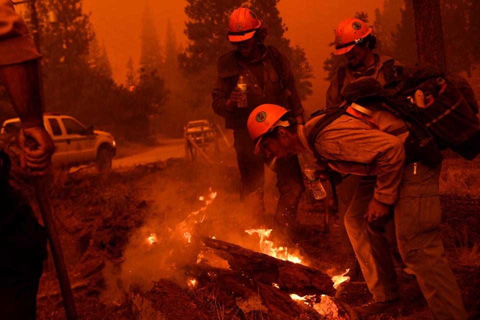 Firefighters improvise and spray water from their mouths to control a small spot fire while waiting for a hose line during the Windy Fire in the Sequoia National Forest near Johnsondale, California on September 22, 2021 (PATRICK T. FALLON/AFP via Getty Images)